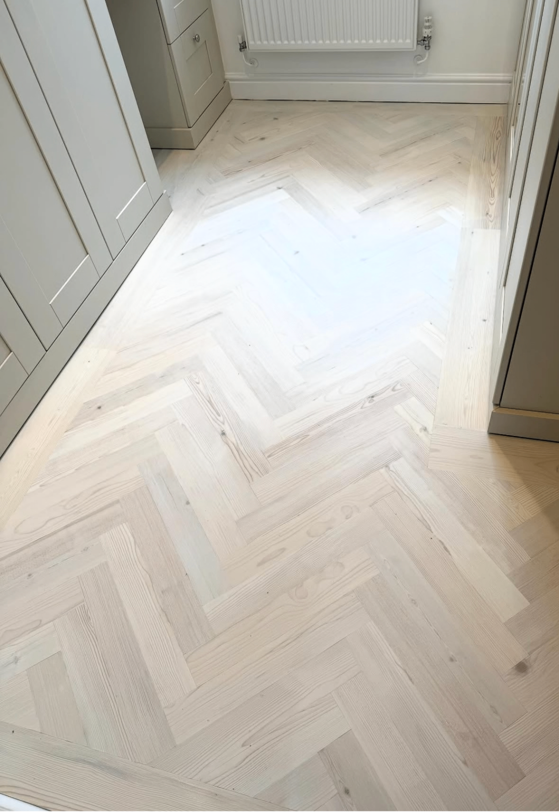Light washed herringbone floor installed in a hallway kitchen space